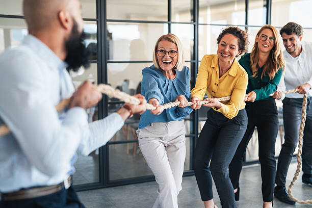 istock Playful colleagues having fun while playing tug-of-war in the office 2240483048