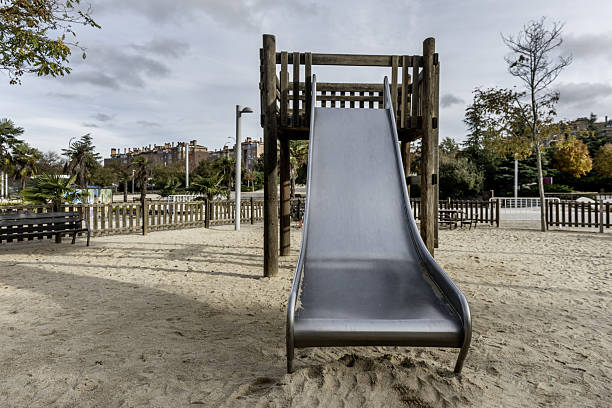 A wide metal slide with a wooden log structure inside a children's playground