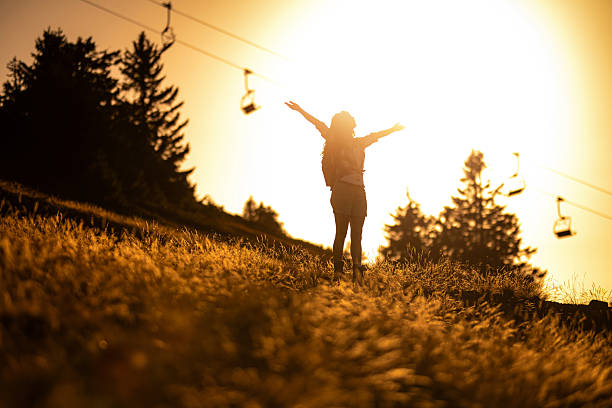 Happy hiker woman enjoying a sunset with arms outstretched in nature.