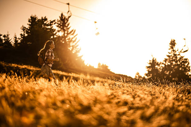 Happy hiker woman running on a mountain in nature while hiking during a sunset. Freedom concept.