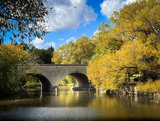 istock Arched stone bridge by river during autumn season 2240489998