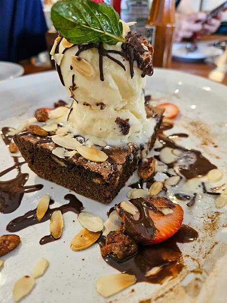 Rich chocolate brownie served with a scoop of vanilla ice cream, nuts, and syrup