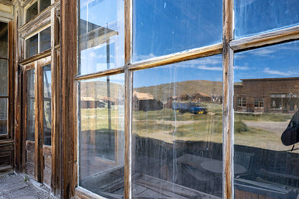 A broken window in a ghost town ruin reflects the high desert sky., Bodie State Historic Park
