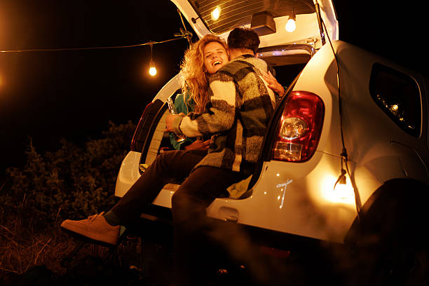 istock Couple enjoying a cozy evening around a car with string lights in a peaceful outdoor setting during nighttime 2240494410