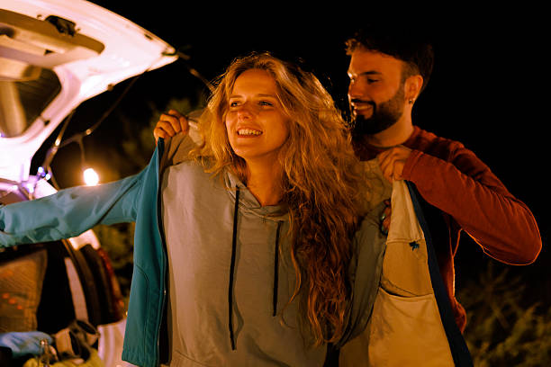 istock Couple enjoying a cozy night outdoors while changing clothes next to their car in a warm evening atmosphere under the stars 2240494437