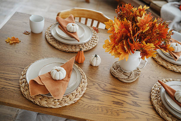 istock Fall table setting with orange maple leaves, mini pumpkins, and woven placemats for Thanksgiving feast. 2240497860