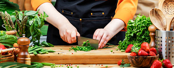 istock In cozy kitchen, private chef skillfully chops fresh vegetables and herbs on a wooden cutting board, focusing on healthy meals 2240501258