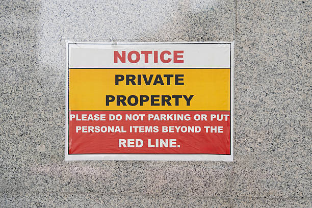 istock A bold warning sign mounted on a textured granite wall communicates restricted access and parking rules, indicating private property and prohibition of leaving personal items beyond the red line. 2240502440