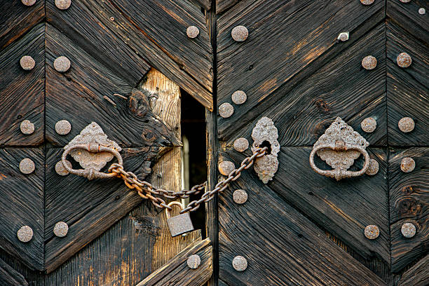 London, UK - Feb 27, 2024 - Chains locking an Entrance old wooden iron doors on the side of an St. Paul's Cathedral. Chained up wooden doors with stone steps leading down, Space for text, Selective focus.