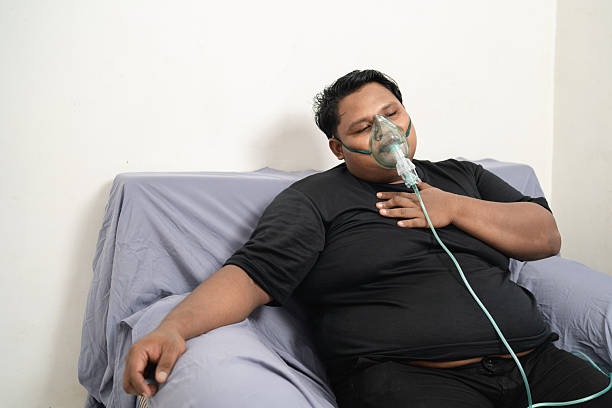 istock Overweight man lying tired using oxygen mask for breathing 2240508499