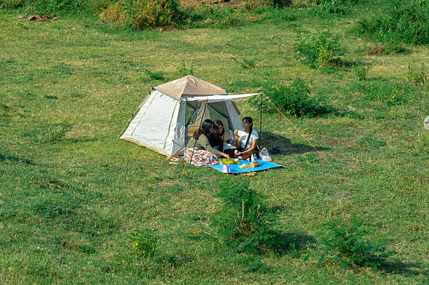 Tent, backpack and camping equipment on green grass in mountains, space for text