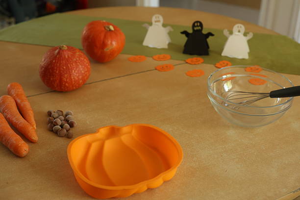 a pumpkin shape cake is being prepared in a kitchen decorated in anticipation for Halloween.