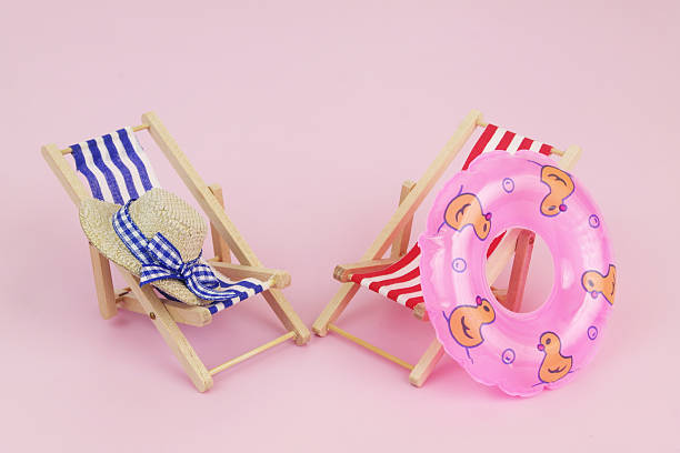 istock Blue and red beach chairs with inflatable ring on pink background. 2240521914