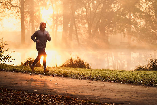 Man jogging in park during autumn sunrise