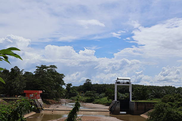 istock An outdoor scene featuring a small dam with a concrete structure atop it, serving as a control center for managing water flow. The dam is situated in a natural environment with trees on both sides 2240535364