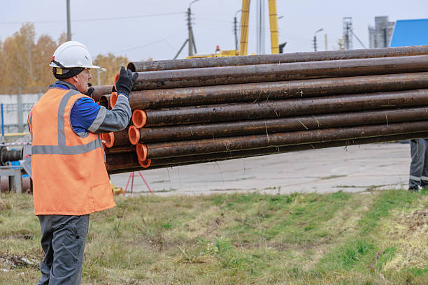 istock Construction Worker Lifting Steel Pipes at Job Site 2240536772