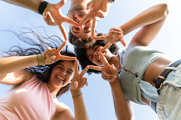 istock Friends showing peace sign gesture forming star against sky 2240537007