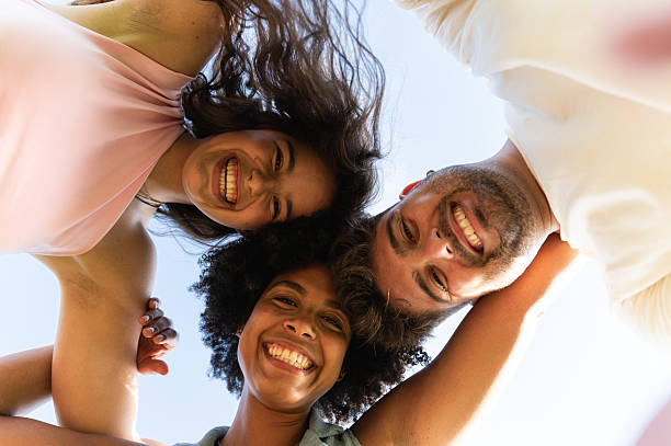 istock Young friends smiling together looking down at camera 2240537015