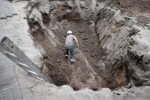 istock Male worker digging deep trench in construction site with safety gear 2240538416