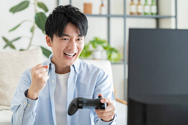 istock Young Japanese man playing video games at home 2240541477