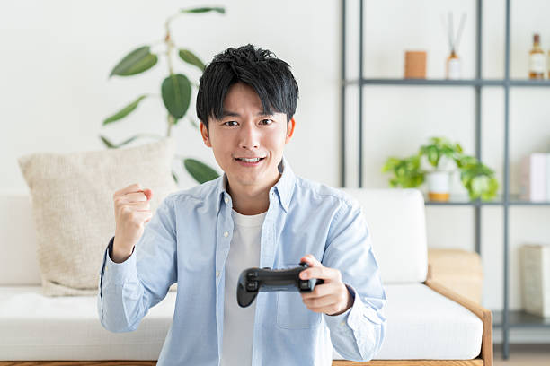 istock Young Japanese man playing video games at home 2240541479