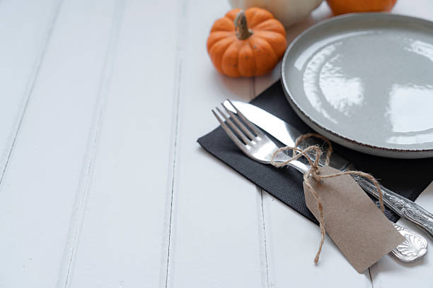 istock A Happy Thanksgiving tag hangs from a small pumpkin and plate as silverware sits on the table 2240542081
