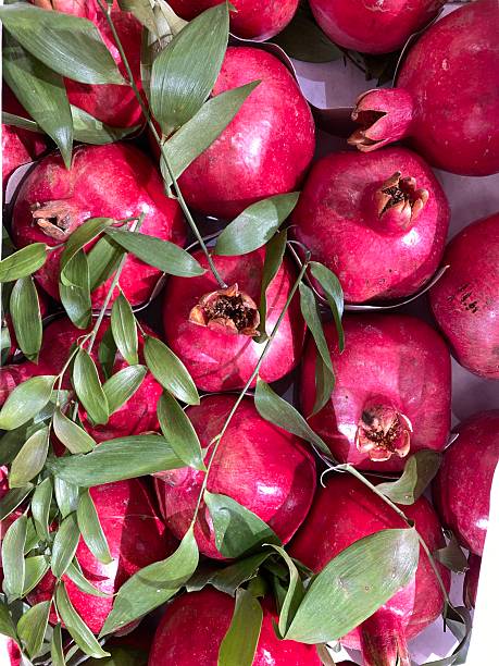 Pomegranates and green leaves create a vibrant natural background with rich color contrast