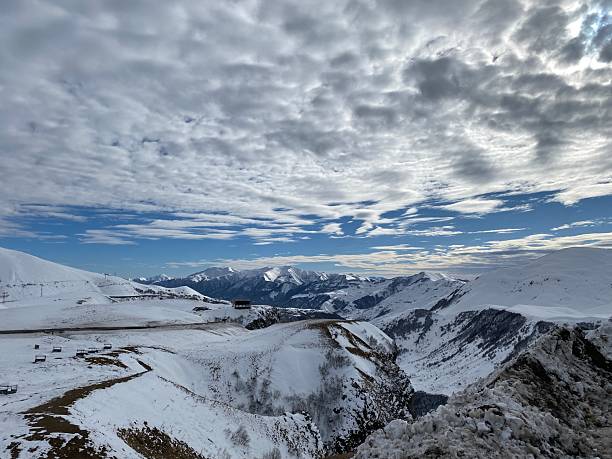 istock Snowy mountain landscape with cloudy sky and distant peaks viewed as a winter background scene 2240542111