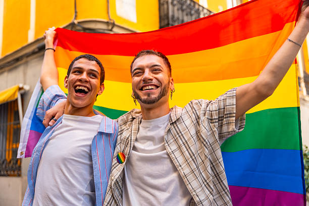 istock Gay men celebrating pride expressing individuality with rainbow flag 2240542167