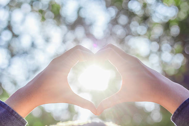 istock Sun shines through the hands symbolically form a heart on nature bokeh background 2240542621