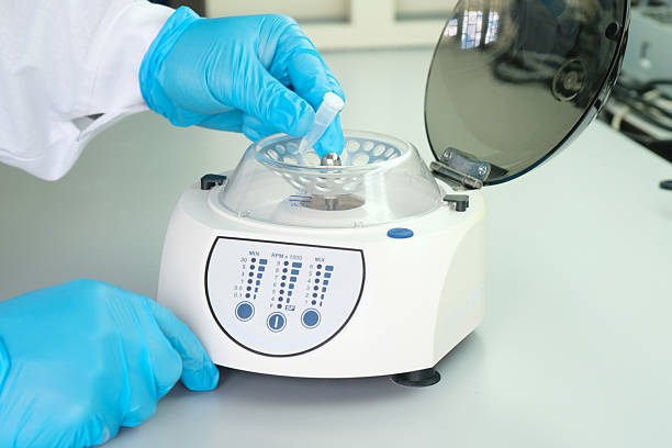 DNA analysis, forensic scientist places a test tube with a sample into a centrifuge, close-up.