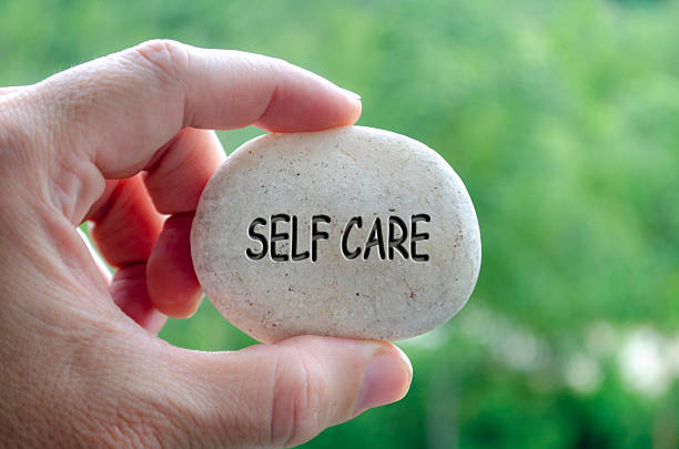 istock Hand holding a white stone with SELF CARE text engraved on it, embodying life purpose of nurturing oneself and maintaining balance. 2240542981