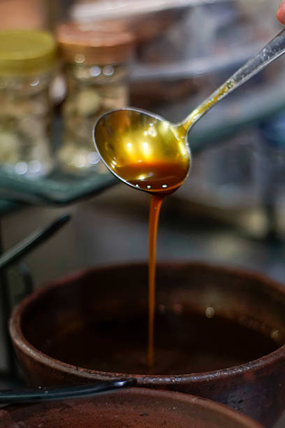 istock Close-up of liquid palm sugar (kinca) poured from spoon into earthenware bowl 2240544070