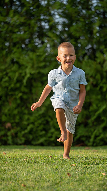 istock Happy little boy running barefoot on green grass 2240547463