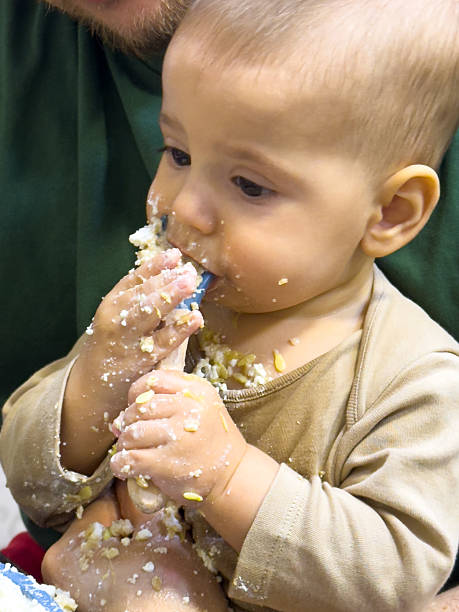 istock Baby Eating Messy Food on Adult's Lap 2240550165
