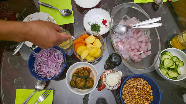 High angle of Peruvian traditional dish - ceviche, corn, potato, slices of anion and other vegetable on glass table.