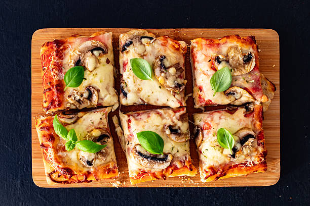 Pizza mushroom al metro with basil leaves on black background