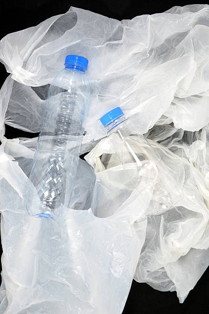 istock Single used plastic bottles and carrybags on black background closeup view 2240560913
