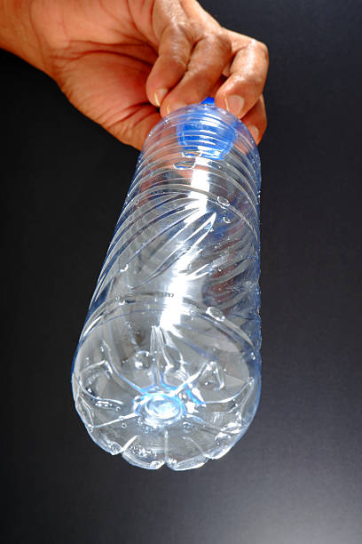 istock Hand holding an empty water bottle closeup view 2240560916