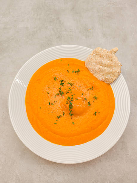 istock Creamy pumpkin soup decorated with thyme and whole grain cracker in a white bowl 2240562337