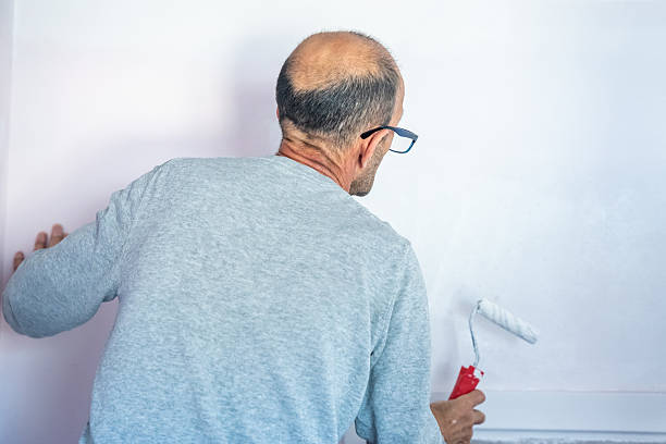 istock Man painting wall with roller in home interior renovation project, back view 2240563614