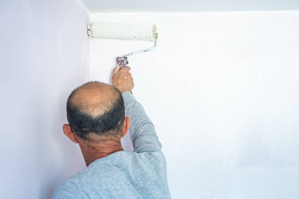 Man painting wall with roller in home interior renovation project, back view