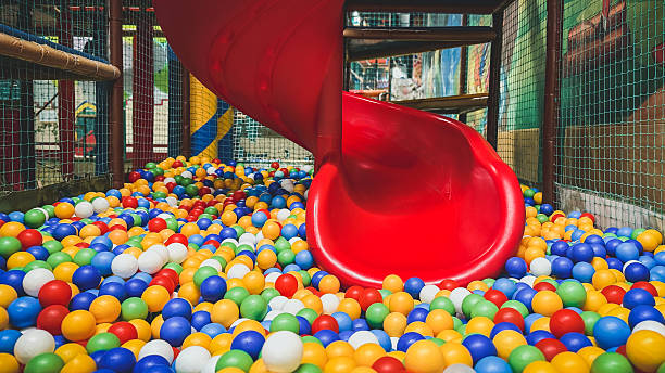 istock Bright red spiral slide ending in colorful ball pit inside indoor playground, filled with multicolored plastic balls, soft structures safety nets, perfect for children s fun entertainment activities 2240568265