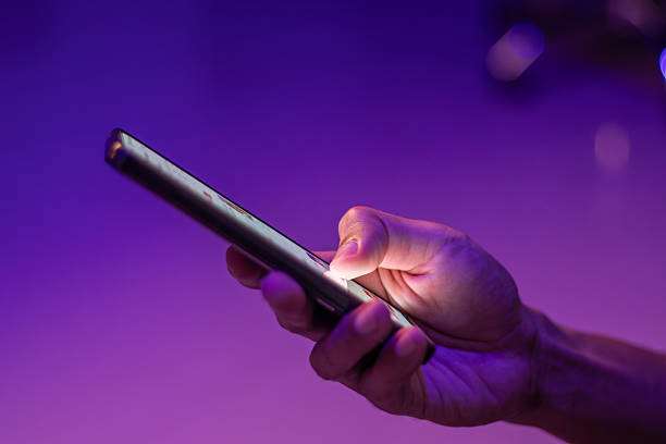istock A man scrolling on social media apps or searching for information online on his smartphone on blue and purple neon lights background 2240569403