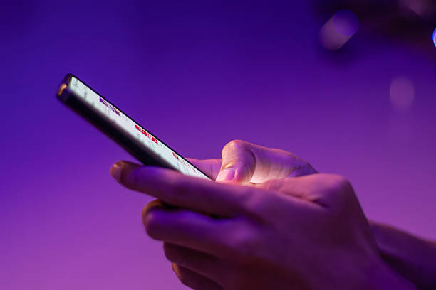 istock A man typing a message on smartphone in dark room with neon light. Chatting or communication concept. 2240569467