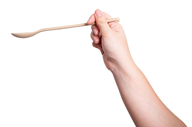 istock Female hand holding a brown plastic spoon isolated on white background. 2240569808