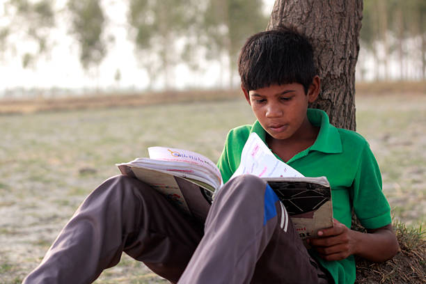 istock Poor Child Reading Book Outdoors in Nature in Rural Setting 2240571215