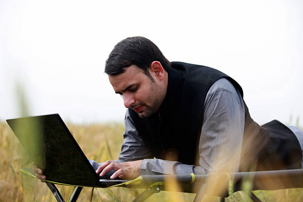 istock Man Working on Laptop While Lying in a Field on a Portable Bed Outdoors 2240571790