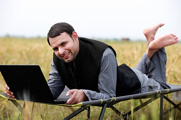 istock Man Working on Laptop While Lying in a Field on a Portable Bed Outdoors 2240571794