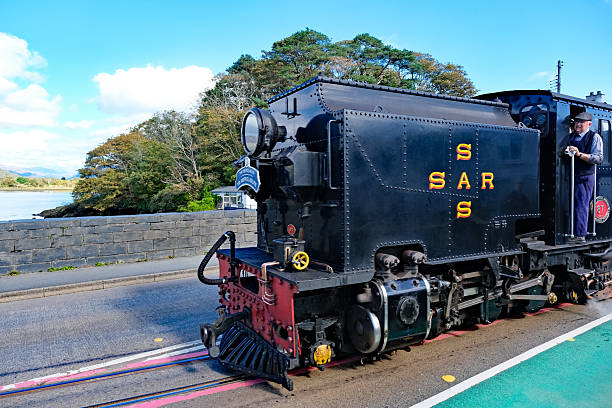 Porthmadog, North Wales, United Kingdom, September 24, 2025. Ffestiniog and Welsh Highland heritage steam railway train leaving the Harbour Station. Sunny Autumn day outdoors.